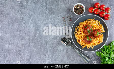 Spaghetti fatti in casa con polpette di salsa di pomodoro e spezie serviti su sfondo grigio. Gustosa pasta cotta e palle di carne a base di carne macinata, cibo ing Foto Stock