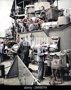 Lavoratori portuali, tra cui un ragazzo rivettatore che lavora con una fucina portatile, riattaccando HMS 'Coventry' durante la seconda guerra mondiale, 1940. HMS 'Coventry' era un incrociatore anti-aereo della Royal Navy di 4290 tonnellate. Foto Stock