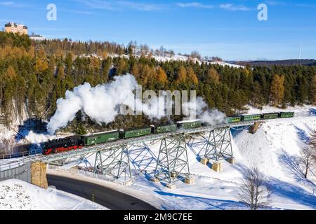 Oberwiesenthal, Germania - 18 dicembre 2022: Treno a vapore Fichtelbergbahn ferrovia locomotiva su un ponte in vista aerea invernale a Oberwiesenthal, Germa Foto Stock