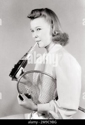 1950S ATLETICA ADOLESCENTE DONNA CON BADMINTON RACKET BERE SODA DA BOTTIGLIA DI VETRO CON PAGLIA DI CARTA - F677 HAR001 HARS STUDIO SHOT COPIA SPAZIO METÀ LUNGHEZZA FISICA FITNESS PERSONE ADOLESCENTE RAGAZZA ATLETICA CANNUCCE B&W POP BENESSERE BEVANDA FLUIDO RICREAZIONE SOFT DRINK CONSUMARE CONSUMO DI IDRATAZIONE ELEGANTE ADOLESCENTE SIP GIOVANI RINFRESCANTI SORSEGGIANDO LA SETE BEVANDE ASSETATE NERO E BIANCO CARBONATA CAUCASICA ETNIA HAR001 VECCHIO STILE Foto Stock