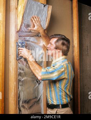 1970S ANONIMO LO FACCIA VOI STESSI PROPRIETARIO DI ABITAZIONE DELL'UOMO USANDO LA PISTOLA DI GRAFFA CHE INSTALLA L'ISOLAMENTO FRA I PRIGIONIERI NELLA PARETE DOMESTICA - KS14387 BAN001 HARS EDIFICI FIDUCIA OBIETTIVI SUCCESSO FELICITÀ SODDISFATTO AVVENTURA TEMPO LIBERO FORZA MIGLIORAMENTO SCELTA ECCITAZIONE PROGRESSO RICREAZIONE ORGOGLIO OPPORTUNITÀ CASE OCCUPAZIONI SORRISI USANDO LA CONNESSIONE CONCETTUALE RESIDENCE DIY HOME RIPARAZIONE ISOLAMENTO METÀ-ADULTO UOMO MEDIO-ADULTO DI PRECISIONE RILASSAMENTO CAUCASICO ETNICITÀ INSTALLARE VECCHIO STILE Foto Stock