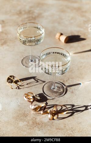 Primo piano di due bicchieri di champagne su sfondo beige soleggiato. Foto Stock