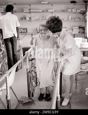 1960S 1970S TERAPISTA DI RIABILITAZIONE DELL'INFERMIERA CHE AIUTA UNA DONNA ANZIANA DALLA SUA SEDIA A ROTELLE A STARE IN PIEDI E UTILIZZARE LE ROTAIE DI RIABILITAZIONE - M8485 HAR001 HARS OCCUPAZIONE VECCHIAIA FORNITORI DI OLLDSTERS FORNITORI DI OLDSTER PROFESSIONISTI CURATIVI AFRO-AMERICANI AFROAMERICANO E NERO ETNICITÀ PROFESSIONI SANITARIE GLI ANZIANI HEALER REHAB OSPEDALI STRUTTURE MEDICO STRUTTURA CENTRO-ADULTO MEDIO-ADULTO DONNA PROFESSIONISTI TERAPEUTA USO NERO E BIANCO CAUCASICO ETNIA HAR001 ANNI GUIDE ALLA MODA AFROAMERICANI Foto Stock