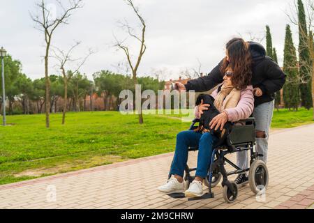 una ragazza che scatta foto con la nonna in sedia a rotelle Foto Stock