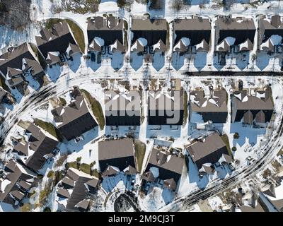 Le case duplex (o abitazione a due famiglie) sono mostrate dall'alto durante una giornata invernale, con la neve che copre principalmente le strade e il terreno. Foto Stock