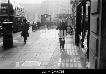 Pedoni che camminano lungo il marciapiede all'estremità occidentale dello Strand, Londra, vicino a Trafalgar Square. L'Arco dell'Ammiragliato può essere visto sullo sfondo. Foto Stock