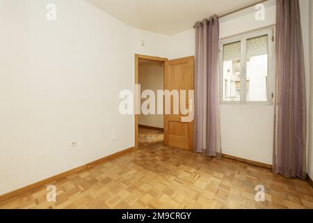 camera vuota con pareti bianche semplici e pavimento in parquet di quercia con doghe a scacchiera e porta abbinata Foto Stock