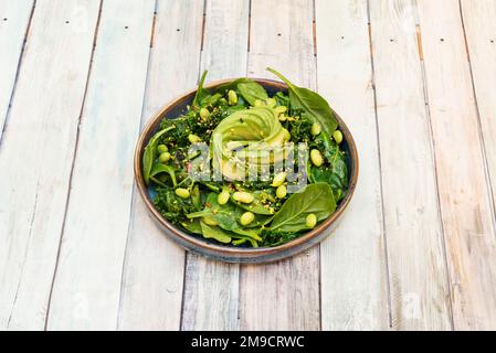 Una meravigliosa insalata vegana con spinaci, alghe wakame, fagioli di edamame e un avocado affettato al centro Foto Stock
