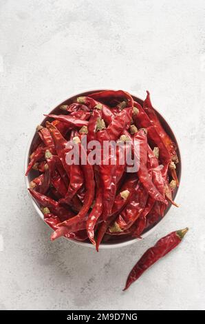 peperoncino rosso secco o peperoncino cayenne in un recipiente o contenitore bianco, closeup di spezie calde isolato su superficie bianca testurizzata con spazio copia Foto Stock