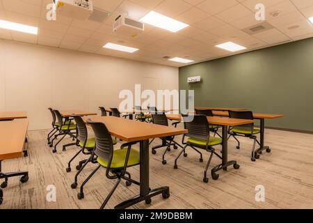 Interno di un ufficio di formazione, riunione, sala conferenze con scrivanie, sedie e lavagna bianca. Nessuno incluso nell'immagine. Foto Stock