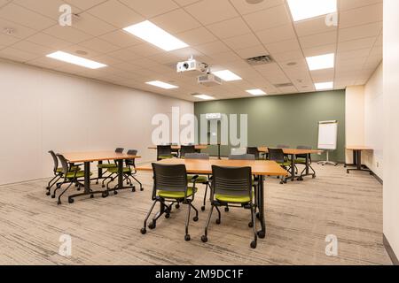 Interno di un ufficio di formazione, riunione, sala conferenze con scrivanie, sedie e lavagna bianca. Nessuno incluso nell'immagine. Foto Stock