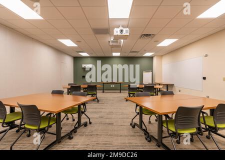 Interno di un ufficio di formazione, riunione, sala conferenze con scrivanie, sedie e lavagna bianca. Nessuno incluso nell'immagine. Foto Stock