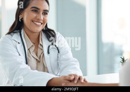 Youre in buone mani, prometto. un giovane e attraente medico seduto e tenendo la mano dei suoi pazienti durante una consultazione nella sua clinica. Foto Stock