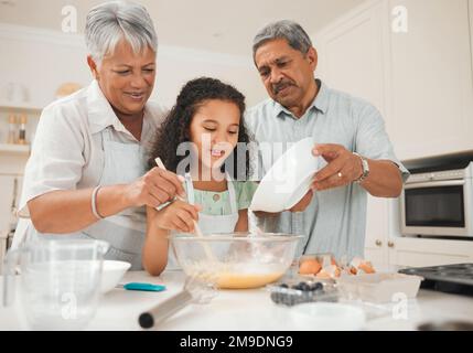 Versare lentamente la farina. un nonno che versa la farina in una ciotola mentre sua nipote si cuoce. Foto Stock