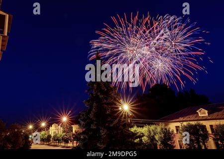 Festive fuochi d'artificio sulla città sullo sfondo del cielo notturno. Esplosioni colorate di saluto Foto Stock