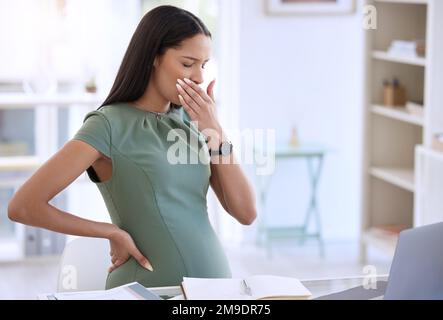 Non mi sento così bene. una giovane donna d'affari incinta seduta da sola nel suo ufficio e coprendo la bocca con la mano. Foto Stock