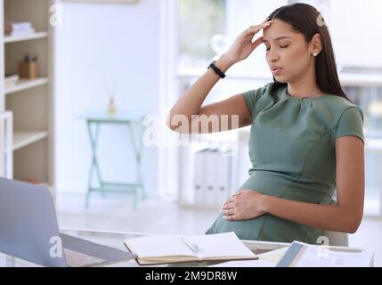 Mi sento così vertigini improvvisamente. una giovane donna d'affari incinta seduta da sola in ufficio e che soffre di mal di testa. Foto Stock