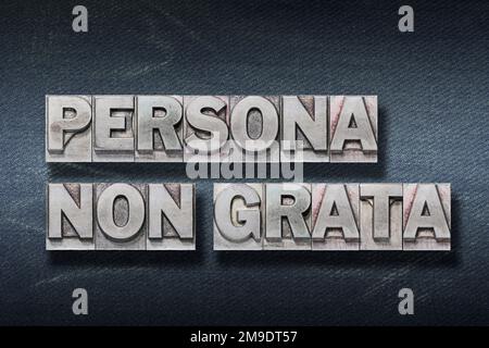 Persona non grata (persona non gradita) frase latina fatta da Letterpress metallico su sfondo di jeans scuro Foto Stock