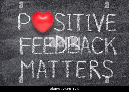 il feedback positivo è importante per la frase scritta sulla lavagna con il simbolo del cuore rosso Foto Stock