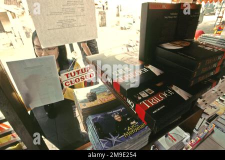 Una donna è fotografata da dietro il vetro di una libreria gestita da Manajemen Qolbu (mq), una filiale di gestione di Daaut Tauhiid, un'istituzione islamica fondata dal famoso predicatore islamico indonesiano, KH Abdullah Gymnastiar, situata a Gegerkalong, Bandung, West Java, Indonesia. Gymnastiar (popolarmente noto come AA Gym), Daarut Tauhiid, e il loro ramo di gestione Manajemen Qolbu (mq), sono riusciti a intensificare il turismo religioso e le attività economiche nella zona di Gegerkalong a Bandung City. Foto Stock