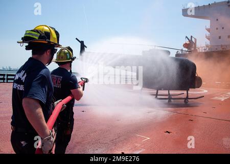 Gli studenti del Maritime Incident Response Team (MITT) del Porto della Virginia estinguono un simulatore di addestramento sul ponte di volo a bordo dell'USNS Montford Point (T-ESD 1). La formazione faceva parte di un simposio MIRT della durata di una settimana in cui più di 120 vigili del fuoco di vari paesi si sono convergenti nella regione per addestrare e collaborare al repellone degli incidenti marittimi. Foto Stock