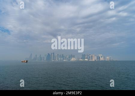 Un dhow tradizionale a Doha, Qatar, con lo skyline moderno della città sullo sfondo. Foto Stock