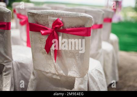 sedie bianche decorate con nastri rosa per la cerimonia di matrimonio closeup Foto Stock