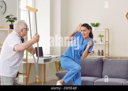 Un anziano aggressivo e arrabbiato che minaccia la sua donna caregiver Foto Stock