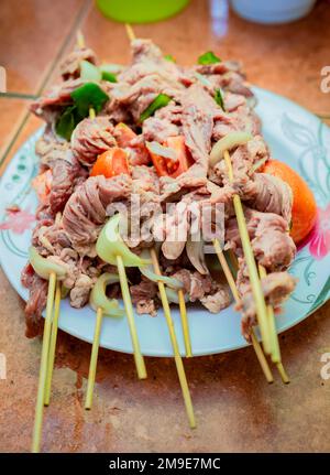 Spiedini di manzo crudo su un piatto. Primo piano di spiedini di carne di manzo cruda con ingredienti. Spiedini di manzo freschi e crudi su un piatto. Preparazione di carni bovine crude Foto Stock