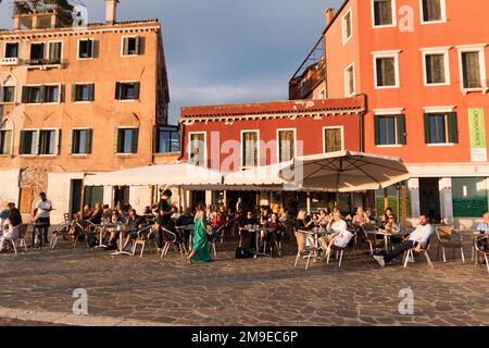 Persone che hanno un drink su una terrazza fuori un ristorante al tramonto a Venezia, Italia Foto Stock