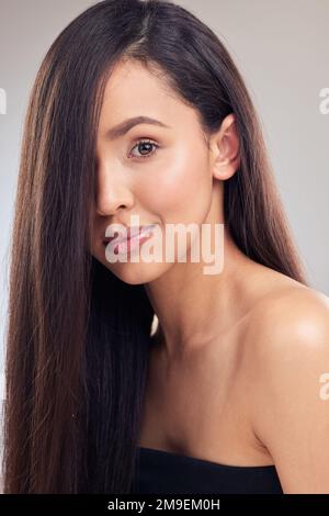 La classe mi viene naturalmente. una giovane donna attraente che si posa da sola in studio con i suoi capelli che coprono metà del suo viso. Foto Stock