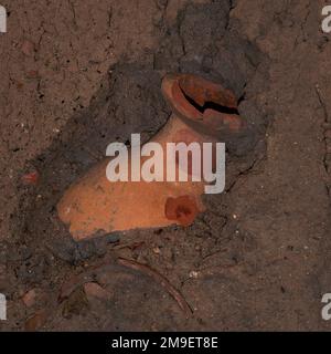 Vista quadrata di anfora in terracotta frantumata o vasetto di stoccaggio in parte sepolto in terreno scavato sul sito archeologico del porto greco e romano del Mar Tirreno di Velia, Marina Ascea, Campania, nella regione del Cilento nel sud Italia. Foto Stock