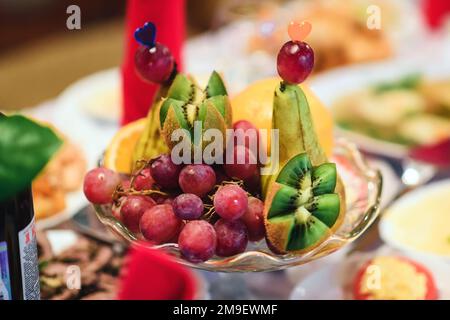 piatto di frutta con uva fresca, kiwi e pera sul tavolo del ristorante Foto Stock