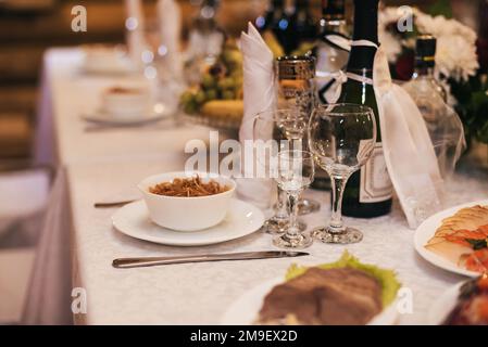 bicchieri e piatti con spuntini sul tavolo festivo del ristorante Foto Stock