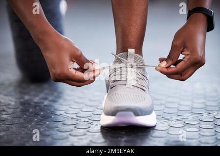 Il suo processo è lento, ma smettere non lo accelera. una donna irriconoscibile che legava le scarpe mentre era in palestra. Foto Stock