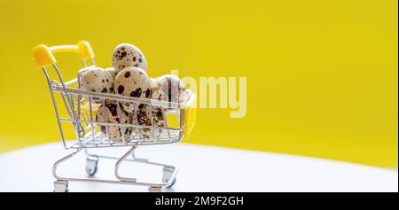 Buona Pasqua sfondo. Uova di quaglia di Pasqua nel carrello della spesa su carta giallo brillante. Concetto festivo Foto Stock