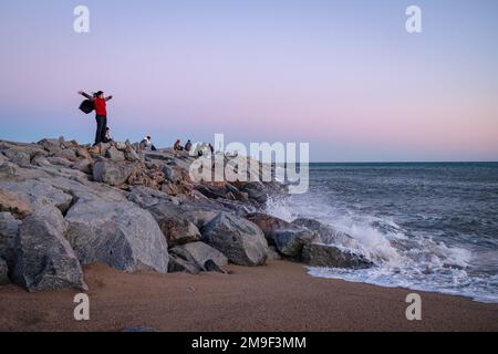 Barcellona, Spagna. 17th Jan, 2023. Una donna si erge sulle rocce mentre le onde si infrangono sul molo della spiaggia di Barceloneta al tramonto. L'arrivo delle tempeste di nome Fien e Gerard ha causato l'allarme meteo in tutta la Spagna a causa di venti molto forti e forti piogge e neve. Credit: SOPA Images Limited/Alamy Live News Foto Stock