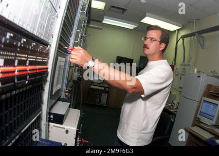 Profilo sinistro ripresa media mentre il civile dell'aeronautica statunitense Brian Hanson si prepara a controllare i livelli di voce su un circuito telefonico in uscita. È un tecnico delle comunicazioni che controlla i sistemi telefonici di base. Hanson supporta lo Squadrone di supporto delle munizioni 731st presso la base aerea di Araxos, Grecce. Base: Araxos Air base Paese: Grecia (GRC) Foto Stock