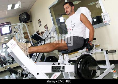 Vista frontale lato sinistro ripresa media come M2 Nevio della Sala, membro militare italiano della Ghedi Air base, Italia, utilizza la pressa per le gambe. Il Services Flight di Ghedi si occupa della palestra e la tiene aperta agli americani e agli italiani per allenarsi durante il giorno. Base: Ghedi Air base Nazione: Italia (ITA) Foto Stock