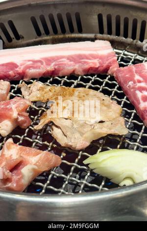 Grigliare carne di maiale pancia su una rete rotonda di ferro barbecue nel ristorante per mangiare, fresco delizioso cibo cucina stile di vita. Foto Stock