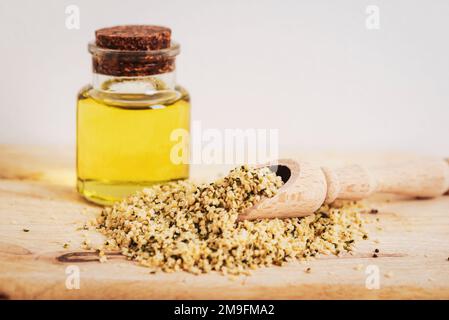 Olio di canapa in bottiglia di vetro e semi su tavola di legno. Foto Stock