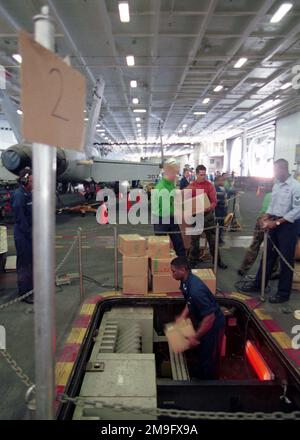 Sailors and Marines utilizza il lavoro di squadra per spostare i negozi su un trasportatore mentre partecipa a un gruppo di lavoro di 500 persone nella baia hangar della USS Harry S. Truman (CVN 75) durante un rifornimento in corso con le navi Navali statunitensi (USNS) Concord (T-AFS 5) e USNS Pecos (T-AO 197). TRUMAN è in stazione nel Golfo Arabo a sostegno dell'operazione SOUTHERN WATCH. SOUTHERN WATCH stabilisce una zona di non volo meridionale sull'Iraq e si estende fino ai confini appena a sud di Baghdad, capitale dell'Iraq. Soggetto operativo/Serie: SOUTHERN WATCH base: USS Harry S. Truman (CVN 75) Foto Stock