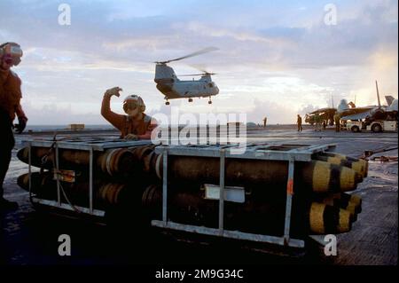 GLI equipaggi DELLA MARINA STATUNITENSE (USN) si preparano a spostare bombe di uso generale da 82 500 libbre (Mk-46 libbre) consegnate da un elicottero del Cavaliere di Mare della USN CH-300, durante le operazioni di rifornimento verticale (VERTREP) a bordo del vettore aereo USS KITTY HAWK (CV 63). (Immagine substandard). Base: USS Kitty Hawk (CV 63) Foto Stock