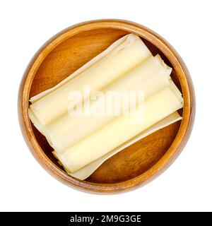 Involtini di formaggio duro svizzero, in una ciotola di legno. Tre fette sottili di Sbrinz, formaggio pieno extra duro, prodotto nella Svizzera centrale. Foto Stock