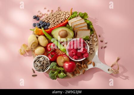 Vista dall'alto di appetitosi lamponi di avocado freschi e sani prugne e mirtilli con frutta secca, patate al formaggio affettate e pomodori composti su rou Foto Stock