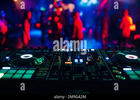 DJ mixer controller Board per mixare musica in un night club a una festa con illuminazione di colori luminosi Foto Stock