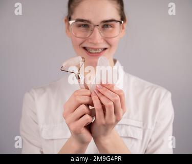 Medico estetista che tiene gouache raschietto e rullo. Foto Stock