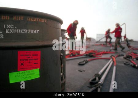 GLI USA Navy Aviation Ordnancemen si preparano ad attaccare ganci di rifornimento verticali ai contenitori di munizioni sul ponte di volo della USS HARRY S. TRUMAN (CVN 75) per il trasferimento alla USS ENTERPRISE (CVN 65) (non mostrato) durante un trasferimento di armi. Base: USS Harry S. Truman (CVN 75) Foto Stock