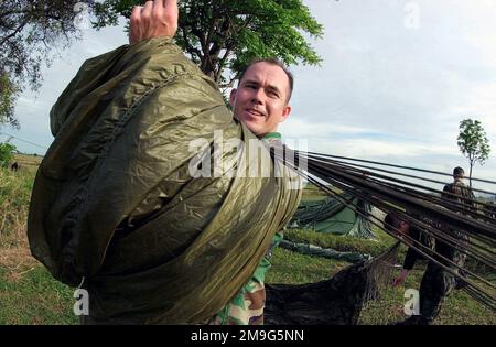 Un membro del servizio dell'esercito statunitense si veste e memorizza il suo paracadute dopo aver partecipato a uno scambio di salto combinato tra Stati Uniti e Thailandia all'esercitazione di quest'anno Cobra GOLD 2001. Uno scambio di salto è una tradizione di salto onorata di tempo che offre ai singoli la possibilità di guadagnare il diritto di indossare le ali di paracadutisti militari stranieri che partecipano allo scambio di salto. Il CG '01 è un esercizio congiunto programmato regolarmente per garantire la pace regionale e rafforzare la capacità delle forze armate tailandesi reali di difendere la Thailandia o di rispondere alle contingenze regionali. L'esercizio di quest'anno, il 20th i Foto Stock