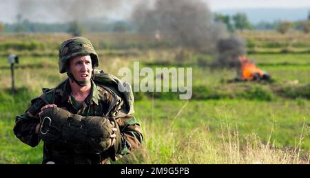 Un membro dei servizi dell'esercito statunitense libera la zona di caduta dopo aver partecipato a uno scambio di salto combinato USA/tailandese durante l'esercizio COBRA GOLD 2001 di quest'anno. Uno scambio di salto è una tradizione di salto onorata di tempo che offre ai singoli la possibilità di guadagnare il diritto di indossare le ali di paracadutisti militari stranieri che partecipano allo scambio di salto. Il CG '01 è un esercizio congiunto programmato regolarmente per garantire la pace regionale e rafforzare la capacità delle forze armate tailandesi reali di difendere la Thailandia o di rispondere alle contingenze regionali. L'esercizio di quest'anno il 20th della serie, sarà Foto Stock